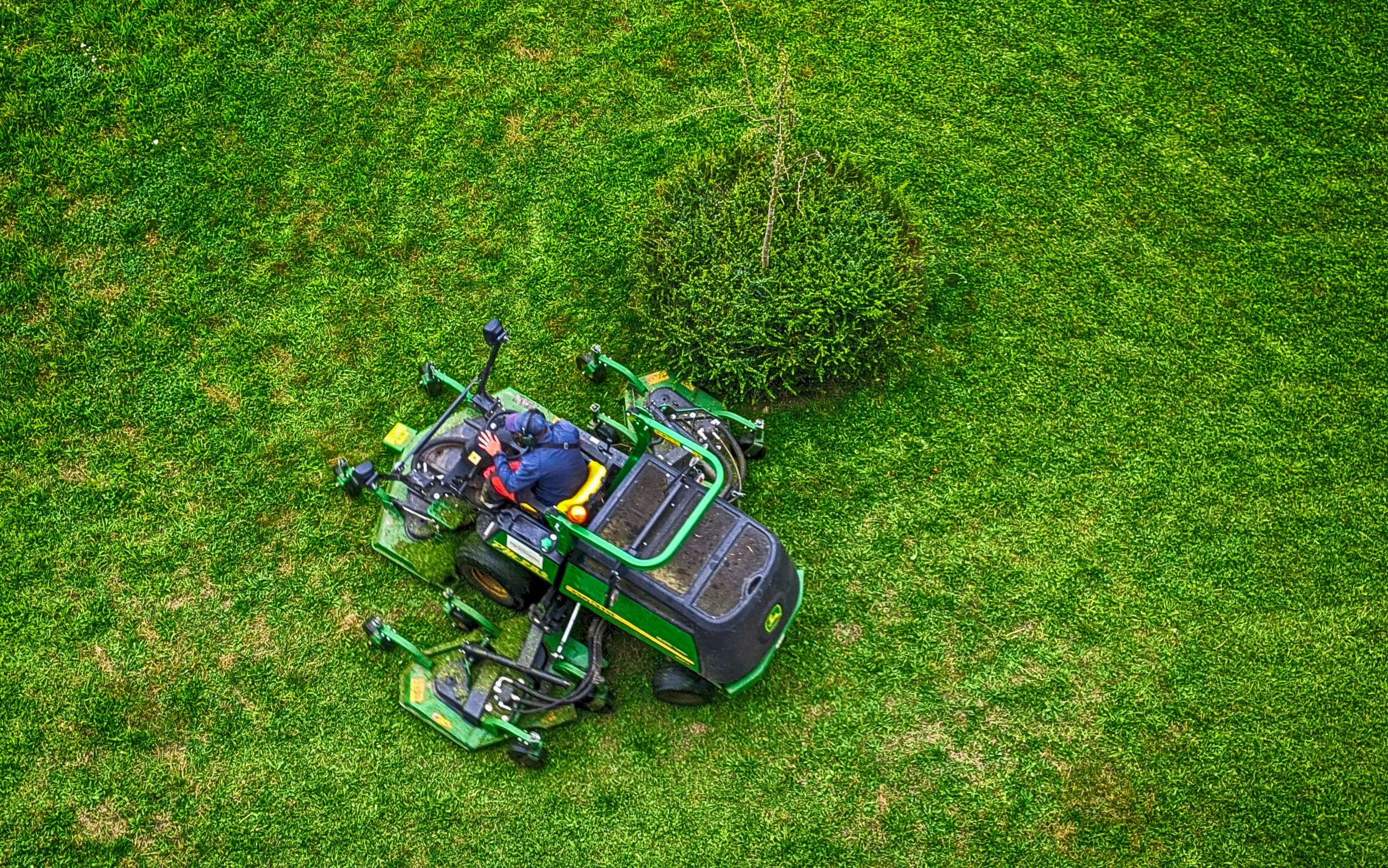 Lawn care technician mowing a commercial property on a ride-on mower